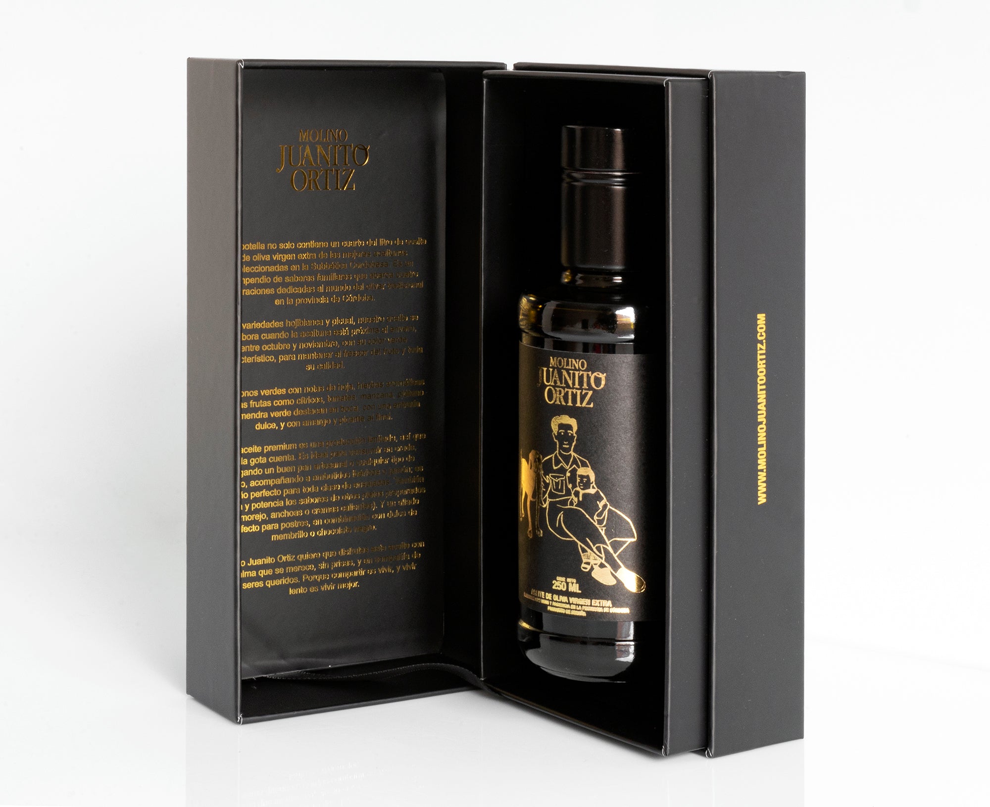Una vista de la botella de aceite de oliva "Molino Juanito Ortiz" dentro de su caja de regalo negra abierta, mostrando el diseño dorado de la botella y la información del producto impresa en el interior de la tapa.