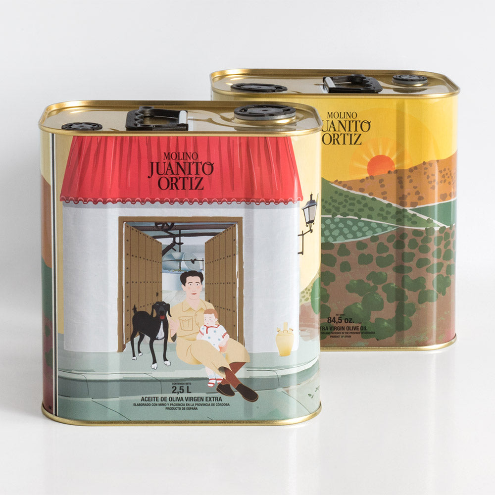 Dos latas cuadradas de aceite de oliva "Molino Juanito Ortiz", una mostrando la ilustración delantera del hombre con el bebé y el perro y la otra la trasera del paisaje al atardecer, vistas desde un ángulo.
